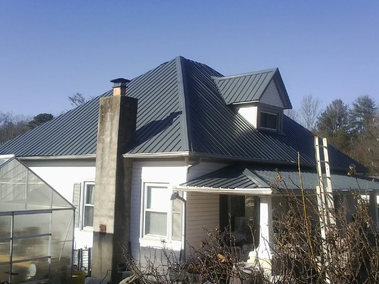 Dark blue standing seam metal roof on a white farmhouse with dormer — Slate & Tile Roof Repair by Roofing Brothers in Metuchen