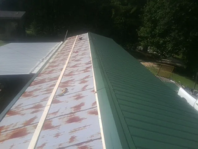 Old rusted panels beside newly installed green metal roofing — Wind Damage Roof Repair by Roofing Brothers in Metuchen