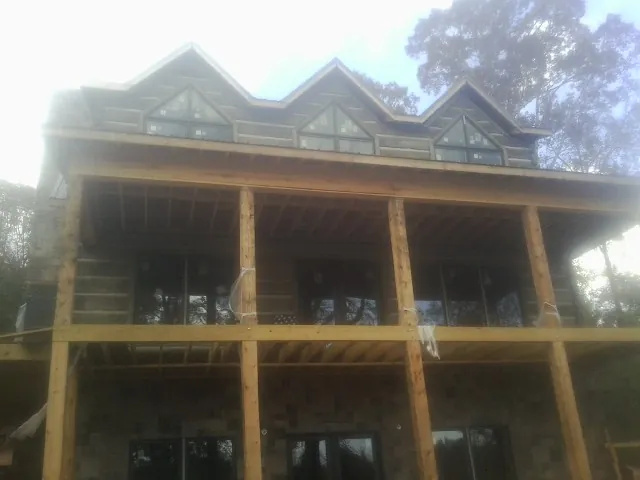 Dormers and porch framing on a large log home under construction — Roof Coating work by our crew in Metuchen