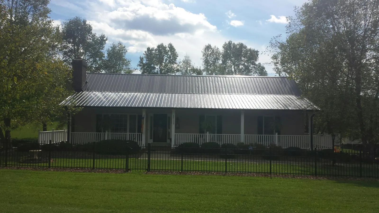 Gray metal roof on a brick ranch with a full width front porch — Gutter Guard Installation work by our crew in Metuchen
