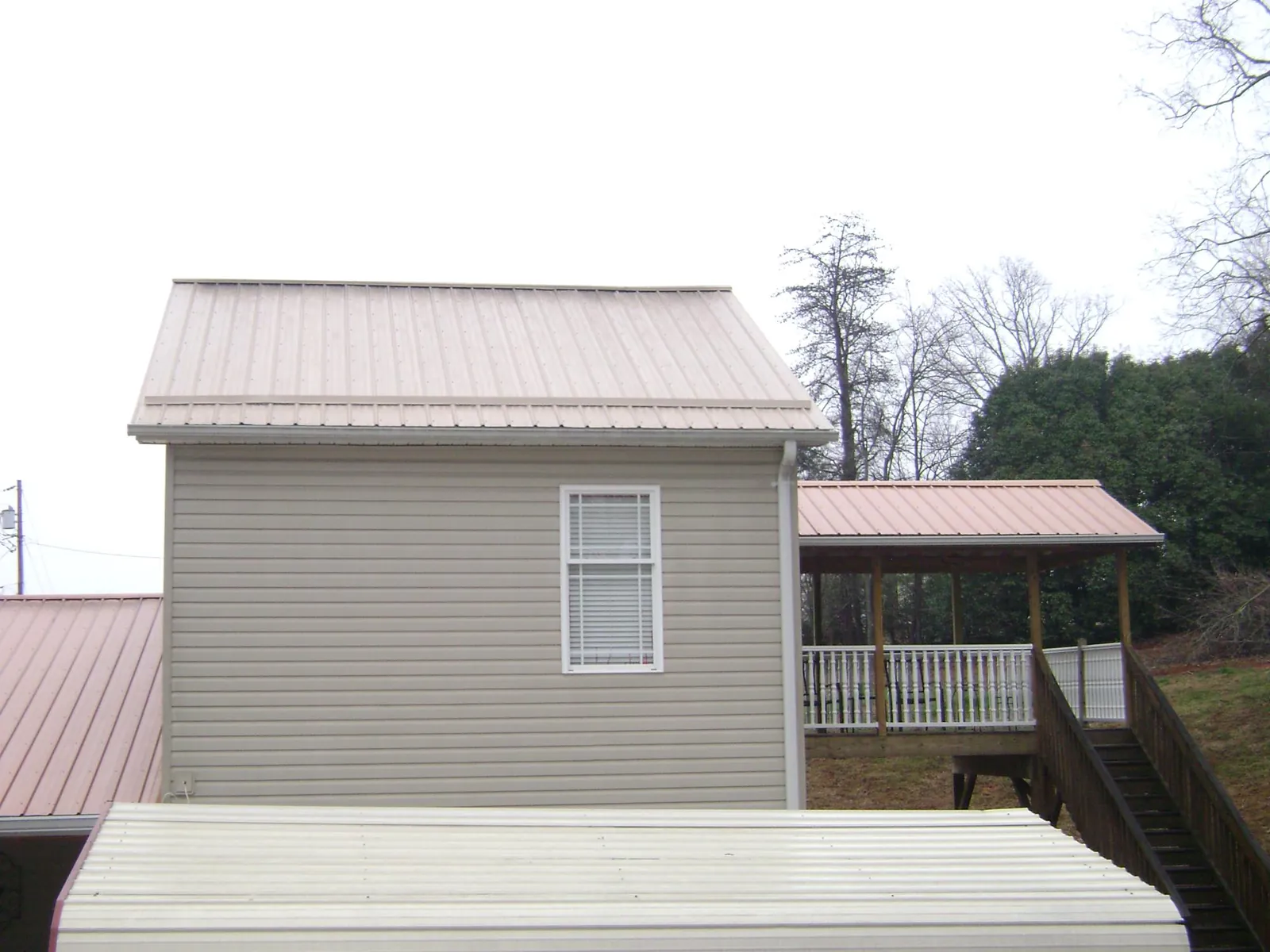 Tan metal roofs on a two story addition and attached porch, from a Roof Replacement job in Metuchen