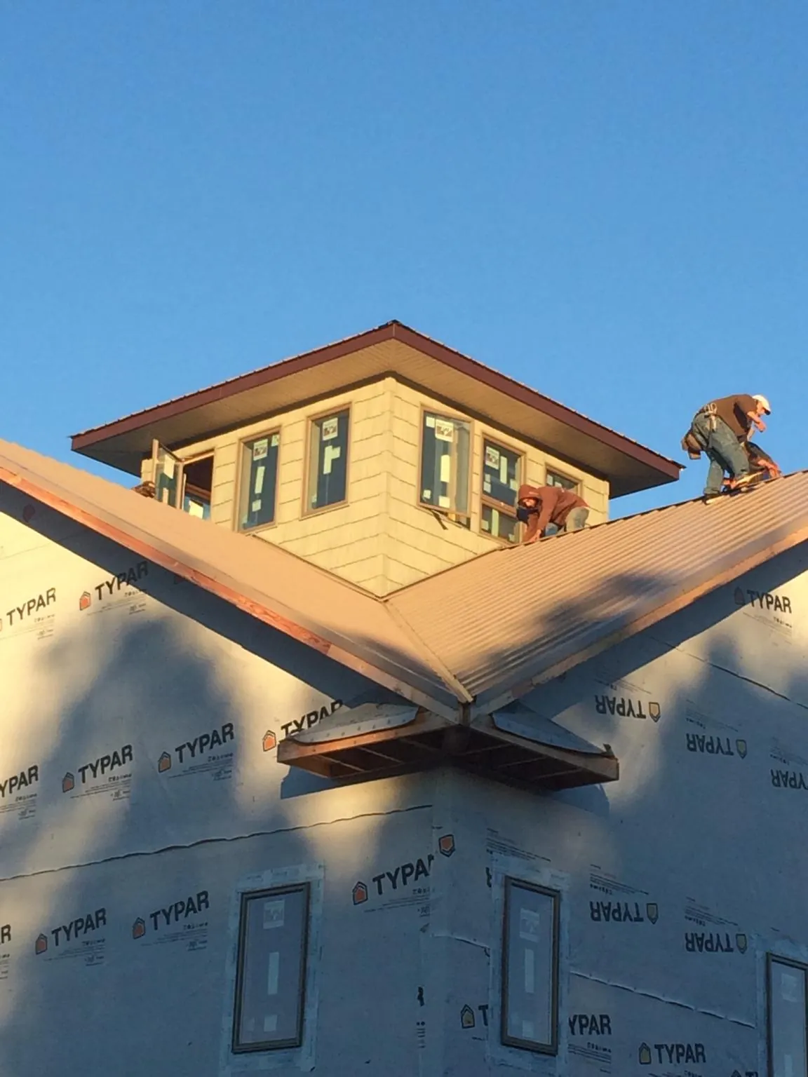Roofers working around a rooftop cupola on a new metal roof at sunset — Roof Waterproofing in Metuchen by Roofing Brothers